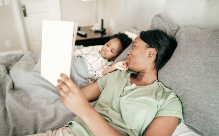 African American mom reading a bedtime story to her toddler as part of her calming bedtime routine.