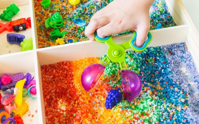 Sensory play bin filled with colorful rice.