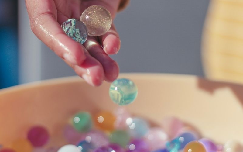 Child's hand playing with water beads as a form of sensory play.